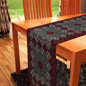 May include: A red, green, and black plaid table runner with a quilted design. The runner is on a wooden table with a chair in the background.