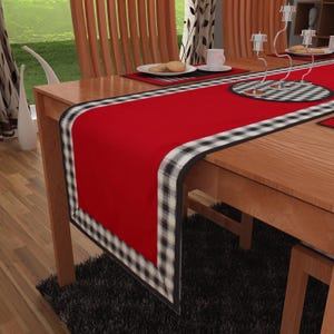 May include: Red and black checkered table runner with a white border. The runner is on a wooden table with two chairs.