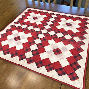 May include: A red and black plaid table runner with a white background. The runner is made of fabric and has a diamond pattern.
