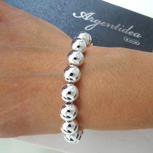 May include: A silver bracelet with a series of large, round, smooth beads.