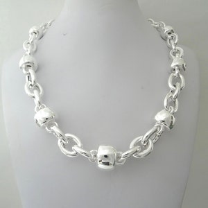 May include: A silver necklace with a chunky chain and large, round, textured beads.