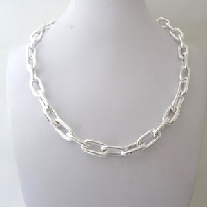 May include: A silver chain necklace with a thick, oval-shaped link design.