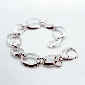 May include: A silver chain bracelet with oval links. The bracelet has a lobster clasp.
