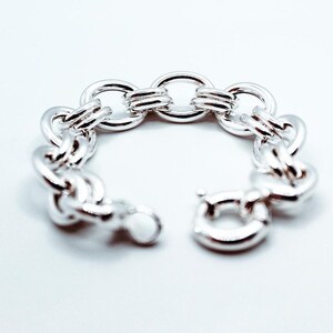May include: A silver chain bracelet with a chunky, interlocking link design. The bracelet has a lobster claw clasp.