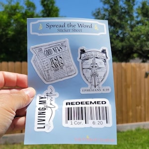 May include: A sticker sheet with a Christian theme. The stickers feature images of a newspaper with the text "Good News Jesus Saves", a knight in armor with the text "Put on the Full Armor of God", a barcode with the text "Redeemed", and a handwritten phrase "Living My Truth".