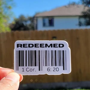 May include: White sticker with black text that reads "REDEEMED" and a barcode. Below the barcode is the text "1 Cor. 6:20".