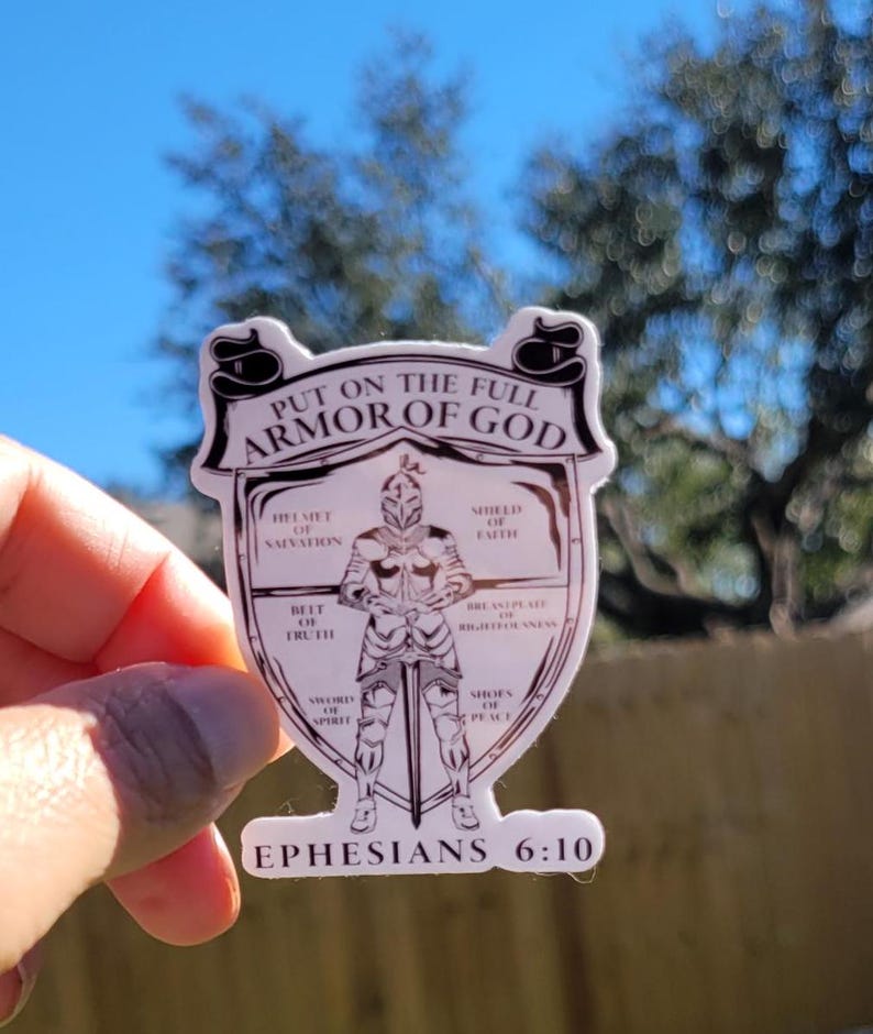 May include: A white sticker with a black outline depicting a knight in armor with a sword. The sticker has the text "Put on the full armor of God" and "Ephesians 6:10". The knight's armor is labeled with different parts of the armor of God, such as "helmet of salvation", "shield of faith", and "sword of the spirit".