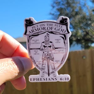 May include: A white sticker with a black and white illustration of a knight wearing armor. The text "PUT ON THE FULL ARMOR OF GOD" is at the top of the sticker. The text "EPHESIANS 6:10" is at the bottom of the sticker.