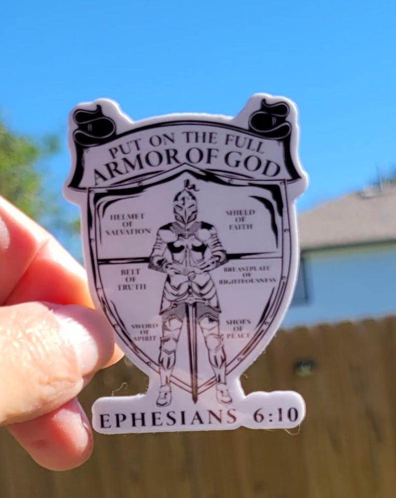 May include: A white sticker with a black and white illustration of a knight in armor. The text "PUT ON THE FULL ARMOR OF GOD" is at the top of the sticker. The text "EPHESIANS 6:10" is at the bottom of the sticker. The knight is wearing a helmet, shield, breastplate, belt, sword, and shoes. Each piece of armor is labeled with a corresponding part of the armor of God from the Bible verse Ephesians 6:10-18.
