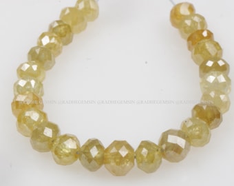 Pode incluir: Um fio de contas de pedras preciosas facetadas amarelas. As contas são enfiadas em um fio branco e estão dispostas em círculo.