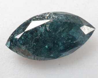 May include: A dark blue marquise-shaped gemstone with a faceted cut. The gemstone has a rough, textured surface.