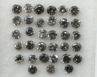 May include: A collection of 25 round, black diamonds in a white tray. The diamonds are arranged in a grid pattern.