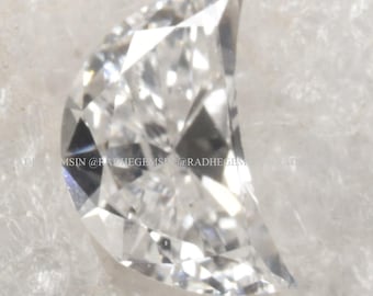 May include: A clear, faceted, crescent-shaped diamond gemstone.