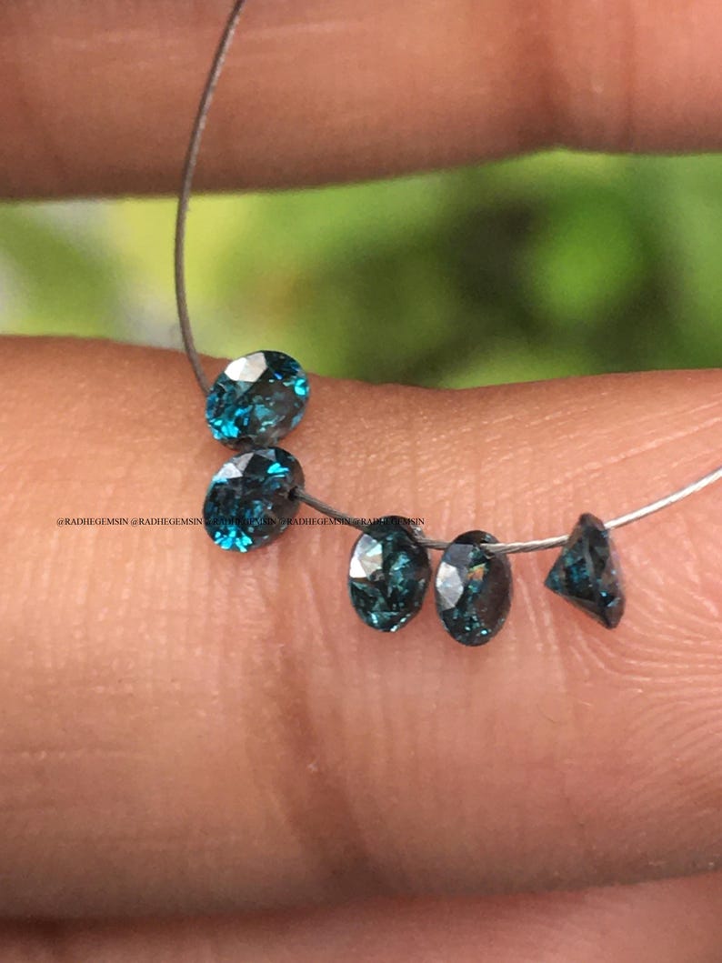 May include: Five loose blue gemstones on a silver wire. The gemstones are round and oval shaped.