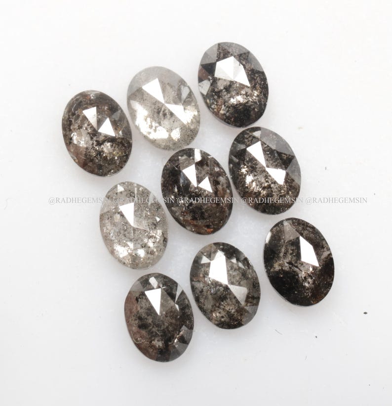 Pode incluir: Uma cole&ccedil;&atilde;o de dez diamantes brutos de corte oval, cinzentos e pretos. Os diamantes s&atilde;o de tamanhos diferentes e t&ecirc;m v&aacute;rias inclus&otilde;es.