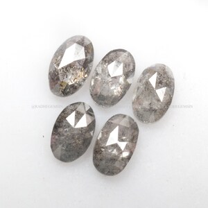 Pode incluir: Cinco diamantes brutos de corte oval, cinzentos e facetados.