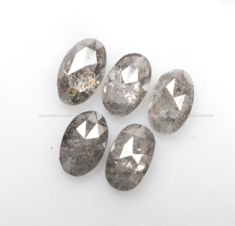 Pode incluir: Cinco diamantes brutos de corte oval, cinzentos e facetados.