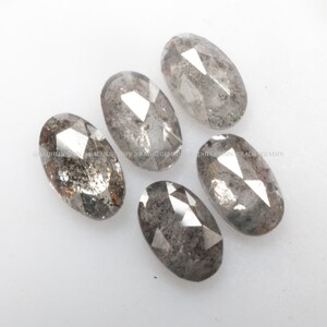 Pode incluir: Cinco diamantes cinzentos facetados de forma oval com um acabamento &aacute;spero e natural.