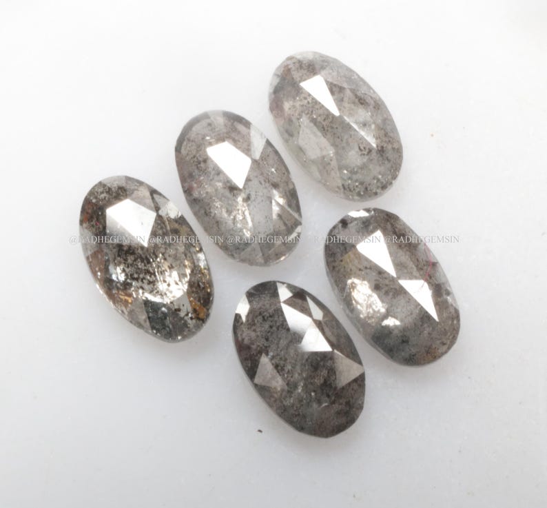 Pode incluir: Cinco diamantes cinzentos facetados de forma oval com um acabamento &aacute;spero e natural.