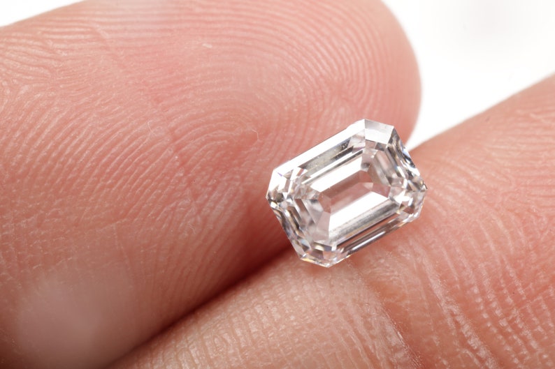 Pu&ograve; includere: Una pietra preziosa di diamante di taglio smeraldo rettangolare trasparente.