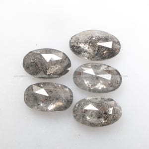 Pode incluir: Cinco diamantes brutos de cor cinza de forma oval e facetados. Os diamantes t&ecirc;m um aspeto &aacute;spero e natural.
