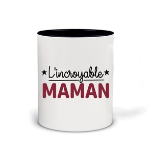 Peut inclure: Mug en céramique blanche avec un bord noir. Le mug a une étoile noire, le texte "L'incroyable" et une ligne noire au-dessus du texte "MAMAN" en rouge.