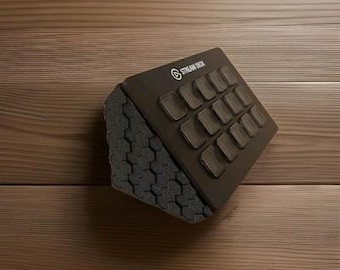 Könnte beinhalten: Ein schwarzes Stream Deck mit mehreren quadratischen Tasten und einer grauen Basis mit Wabenmuster. Das Stream Deck-Logo ist in der oberen linken Ecke sichtbar. Das Gerät befindet sich vor einem Holzuntergrund.