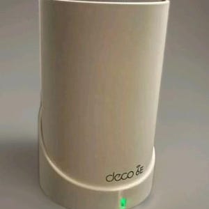 May include: A cylindrical, off-white Deco 6E wireless router with a rounded base and top. The device has a green LED indicator and the Deco 6E logo printed on the front. A white cable extends from the base.