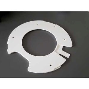 May include: A white, semi-circular plastic component with a central circular opening and several smaller holes. The component has a notched design on one side and is set against a dark gray background.