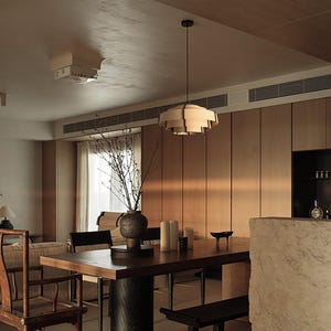 Puede incluir: Un comedor con una mesa de madera oscura, un banco negro y sillas de madera. Una l&aacute;mpara decorativa cuelga sobre la mesa. Un jarr&oacute;n con ramas y velas est&aacute; sobre la mesa. Las paredes son de paneles de madera.
