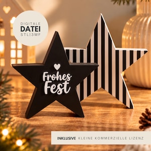 Könnte beinhalten: Zwei sternförmige Dekorationsobjekte. Eines ist einfarbig schwarz mit einem weißen Herz und dem weißen Schriftzug "Frohes Fest" auf der Vorderseite. Der zweite Stern steht dahinter und ist mit einem schwarz-weißen vertikalen Streifenmuster versehen.
