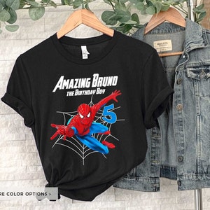 Op de afbeelding: Zwart T-shirt met een rode en blauwe Spiderman-afbeelding, een spinnenweb en de tekst "Amazing Bruno The Birthday Boy" en het nummer "5".