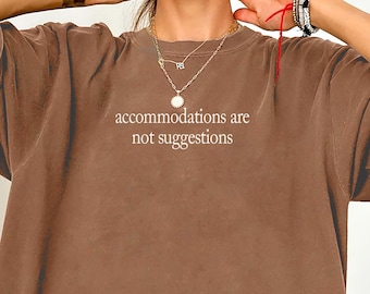 May include: Espresso-colored oversized t-shirt with the text "accommodations are not suggestions" in white. The shirt has a relaxed fit and short sleeves. The word "Espresso" is written in cursive at the bottom left.