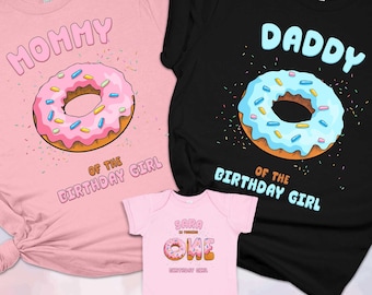 May include: A light pink t-shirt with a pink donut graphic and text reading Mommy of the Birthday Girl, a black t-shirt with a blue donut graphic and text reading Daddy of the Birthday Girl, and a light pink baby bodysuit with donut text.