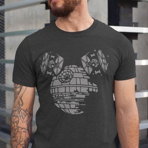 May include: A dark grey t-shirt featuring a white graphic of the Death Star from Star Wars with two TIE fighters flying above it.