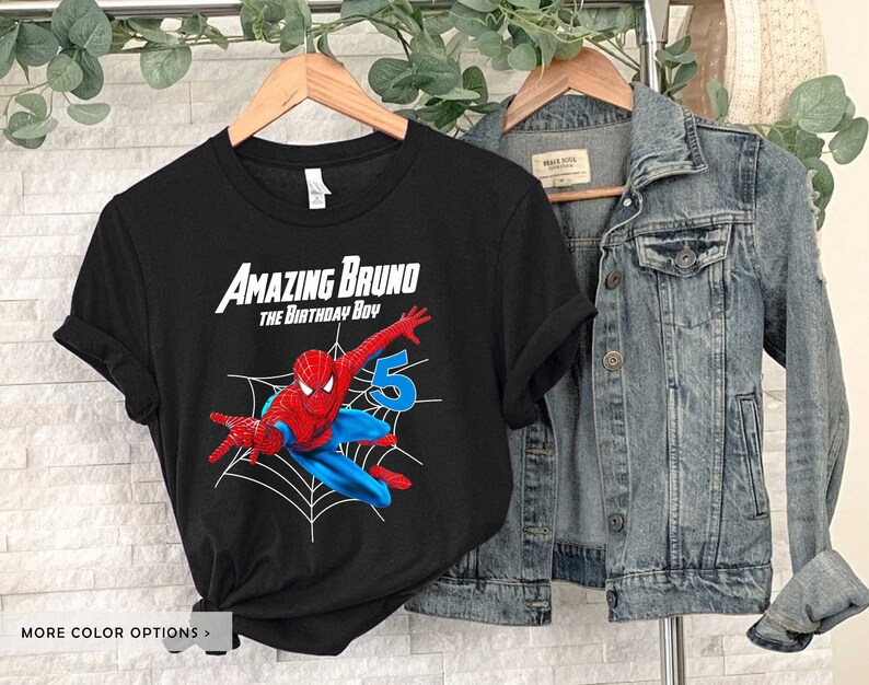 Op de afbeelding: Zwart T-shirt met een rode en blauwe Spiderman-afbeelding, een spinnenweb en de tekst "Amazing Bruno The Birthday Boy" en het nummer "5".