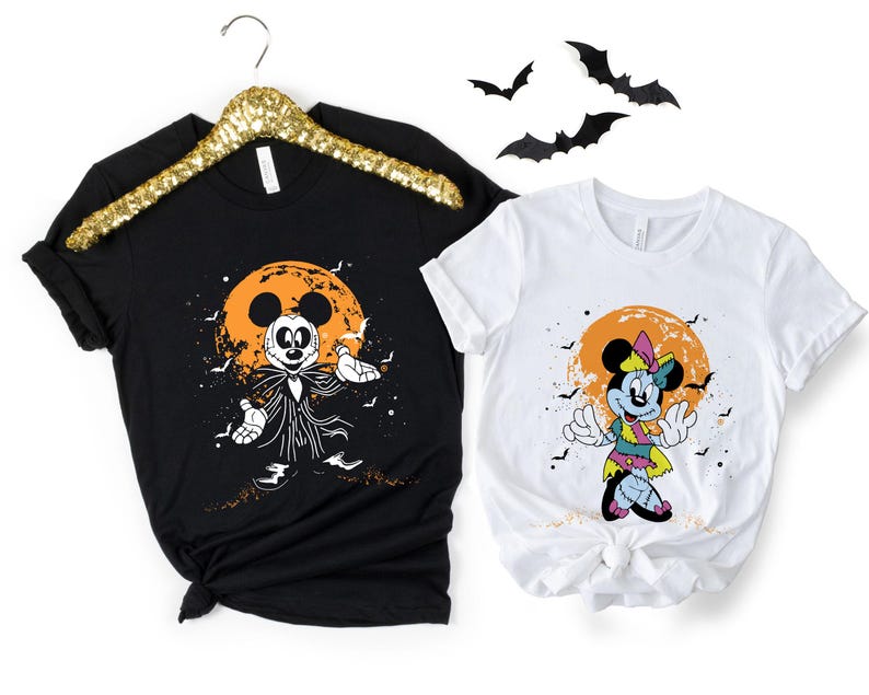 May include: Two black and white t-shirts with a Halloween theme. The shirt on the left features Mickey Mouse dressed as a zombie with a jack-o-lantern moon in the background. The shirt on the right features Minnie Mouse dressed as a zombie with a jack-o-lantern moon in the background.