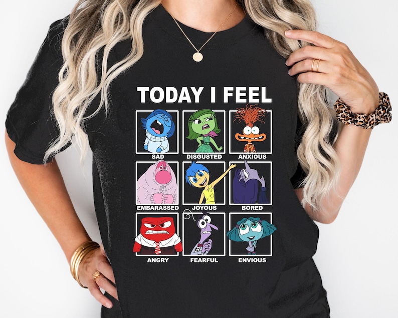 Pu&ograve; includere: Maglietta nera con il testo "TODAY I FEEL" e una griglia di nove personaggi dei cartoni animati che rappresentano diverse emozioni. I personaggi sono del film Inside Out. Le emozioni includono tristezza, disgusto, ansia, imbarazzo, gioia, noia, rabbia, paura e invidia.