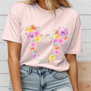 May include: A pink t-shirt with a floral Mickey Mouse design. The flowers are in shades of yellow, orange, pink, and purple.