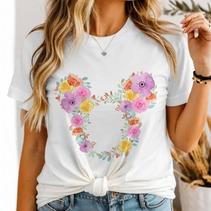 May include: White t-shirt with a floral design in the shape of Mickey Mouse ears. The flowers are in shades of pink, purple, yellow, and orange.