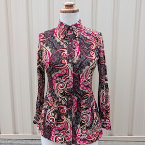 以下が含まれることがあります： 黒い持ち手と「But First, Coffee」の文字が黒い手書き風フォントで書かれた白いセラミックマグ。マグカップは白い表面に置かれています。