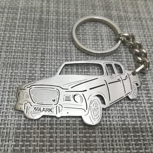 May include: Silver metal keychain featuring a cutout design of a vintage car with the license plate "50LARK".