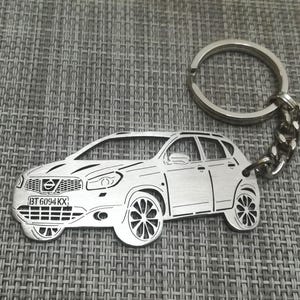 Puede incluir: Un llavero de metal plateado con un recorte detallado de un Nissan Qashqai con la matrícula "BT 6094 KX".