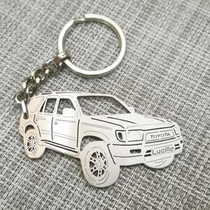 May include: Silver keychain featuring a detailed cutout of a Toyota SUV. The keychain includes the word "Toyota" and the name "Lucille" on the vehicle.