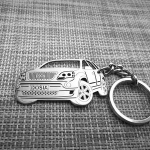 May include: Silver metal keychain featuring a detailed cutout of a car with the word "DOSIA" on the license plate. The keychain has a silver metal ring.