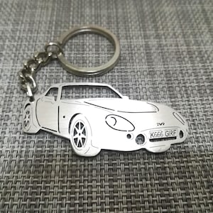 May include: A silver metal keychain featuring a detailed outline of a sports car with the registration plate "K666 GRF".