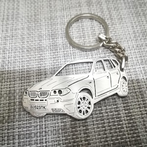 Może przedstawiać: Srebrny metalowy brelok do kluczy z detalicznym konturem srebrnego BMW X3 z tablicą rejestracyjną "B1523TK".