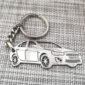 Op de afbeelding: Een zilveren metalen sleutelhanger met een gedetailleerde omtrek van een auto met het kenteken "7WWY510".