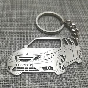 May include: A silver-colored car-shaped keychain with a license plate that reads "PB 5299 TP". The keychain is attached to a metal ring and chain. The car design features detailed outlines of the vehicle's body, wheels, and windows.