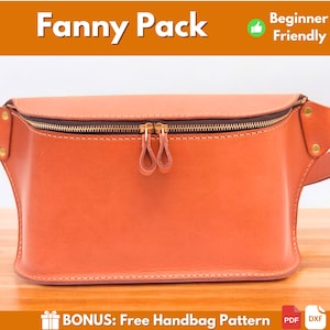 May include: A brown leather fanny pack with a gold zipper and a gold buckle. The fanny pack is on a wooden surface. Beginner Friendly.